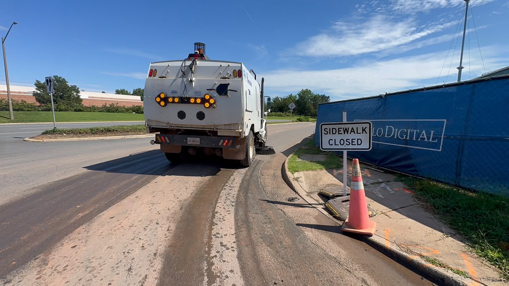 Street sweeper cleaning a roadway near an active work zone